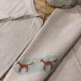 Dettaglio applicazioni in tessuto Volpi su cotone tinta unita